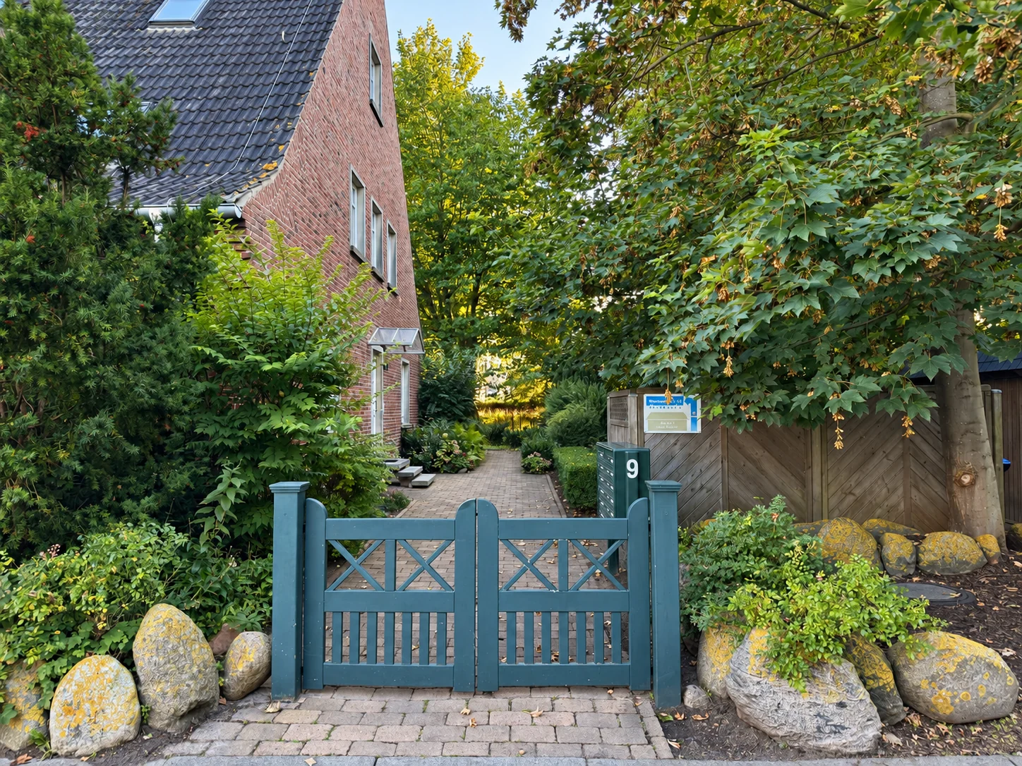 Grünes Gartentor mit Hausnummer 9 und Weg neben dem Haus